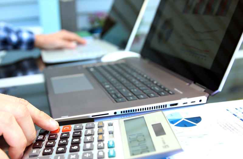 A bookkeeper using a calculator and entering amounts into a computer